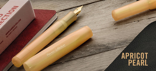Apricot Kaweco Collection fountain pen with gold nib, shown uncapped beside its cap on a wooden desk with box and notebook.